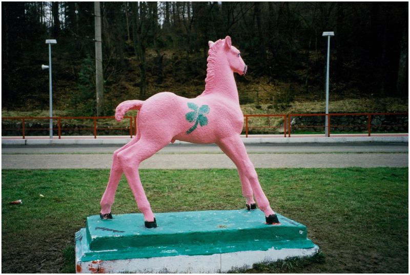 Holbein-Pferd rosa mit grünem vierblättrigem Kleeblatt auf grünem Sockel