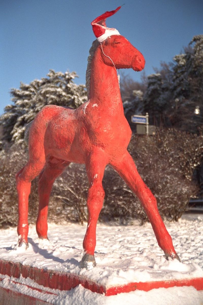 Holbein-Pferd rot mit Weihnachtsmütze im Schnee